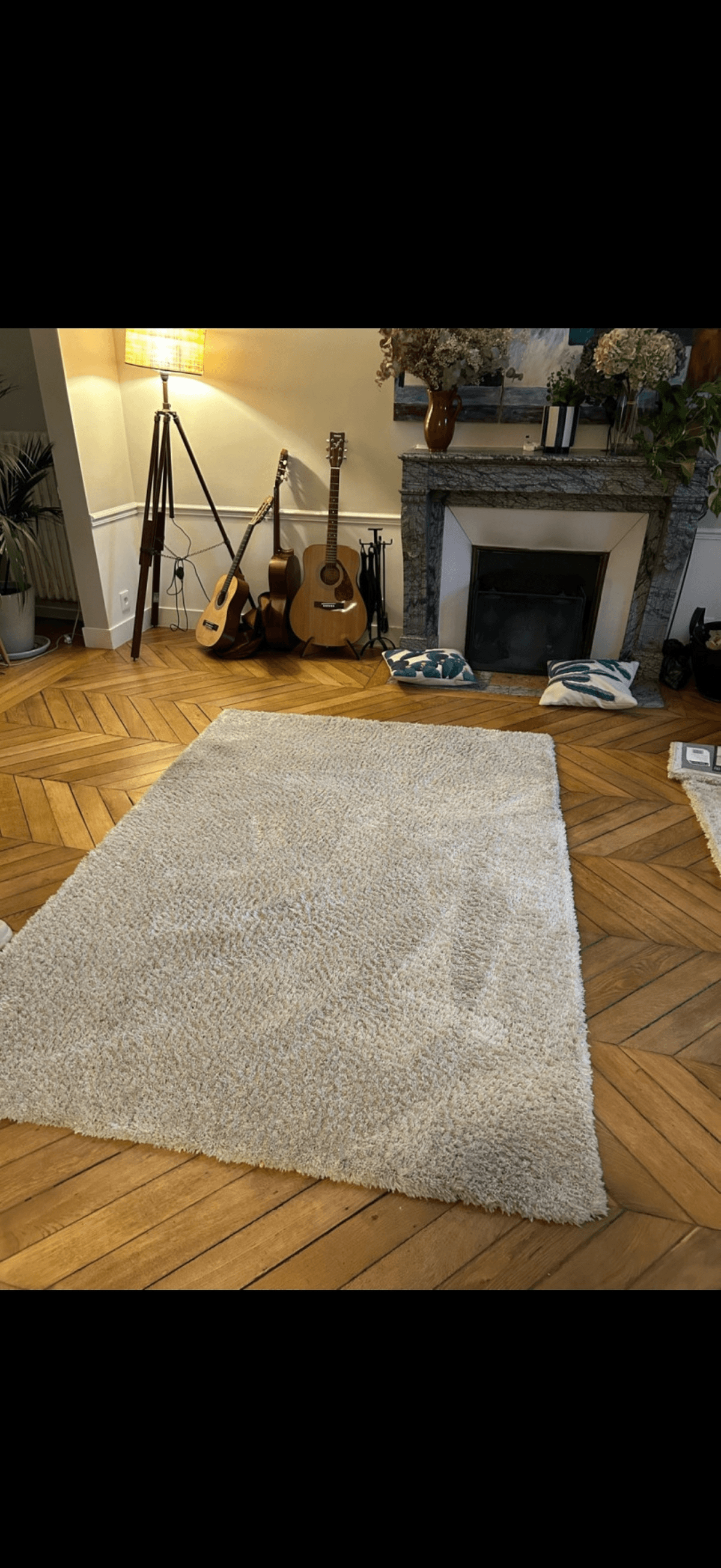 Salon parisien parquet chevrons avec tapis shaggy blanc nettoyé par Nesfag Services, cheminée et guitares en arrière-plan